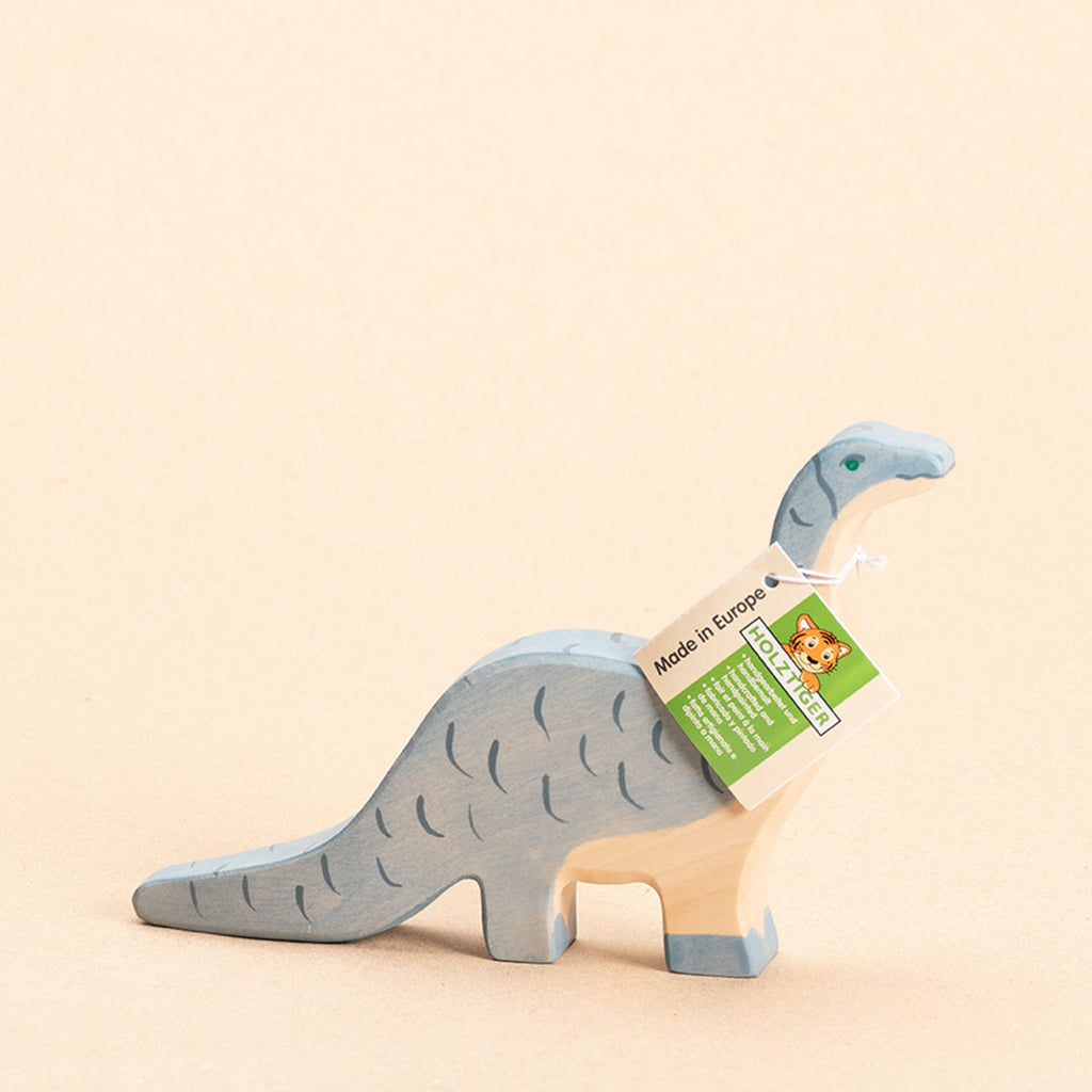 Brontosaurus aus Holz. Blau bemalt mit dunkelblauen Strichen. Nach rechts schauend mit Holztiger Etikett