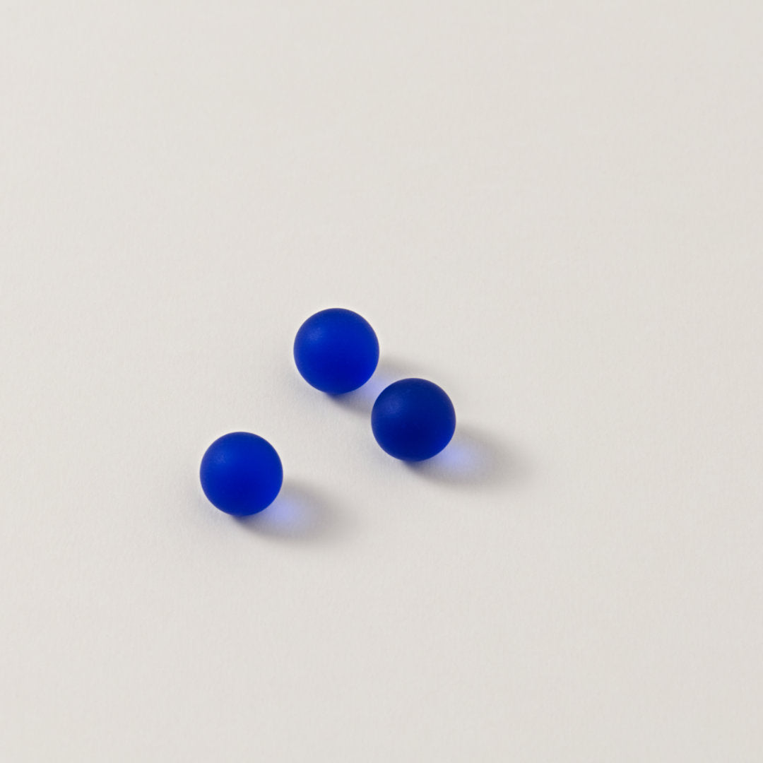 Drei matte, blaue Murmeln