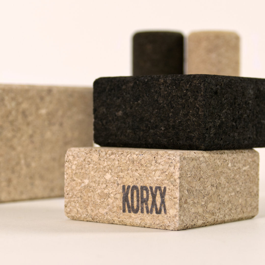 Detail gestapelte Korkbausteine in schwarz und naturfarben mit gefasten Kasten und Logoschriftzug