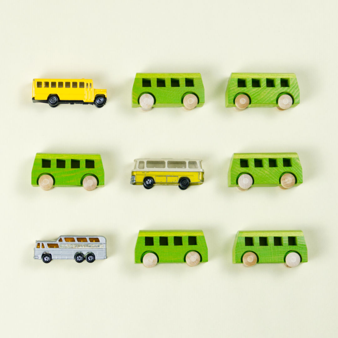 Anordnung von kleinen grünen Spielbussen aus Holz und anderen Mehrpersonenfahrzeugen