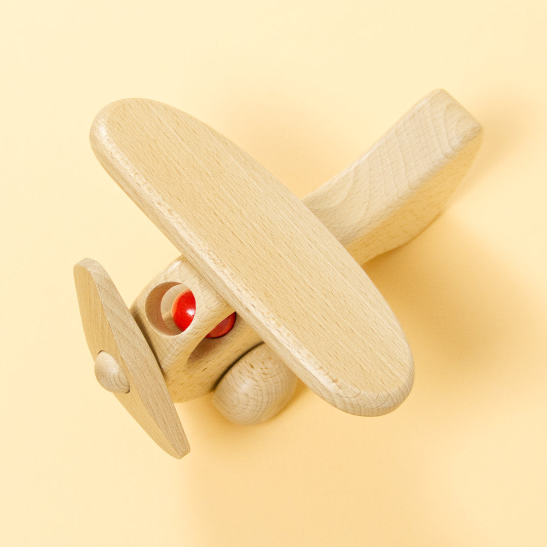 Holz-Flugzeug aus naturbelassenem Buchenholz und roter Holz-Figur