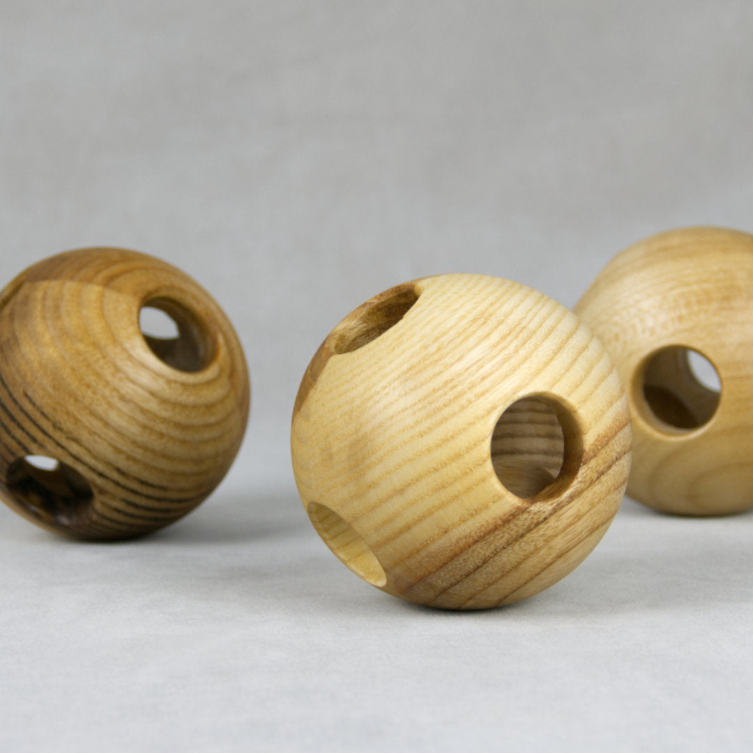 Greiflinge aus Holz in Ballform mit kreisrunden Öffnungen mit unterschiedlichen Holzmustern