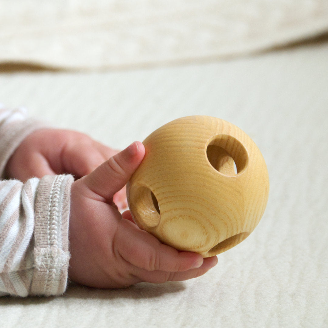 Der Greifling aus Holz liegt angenehm in der Kinderhand