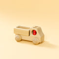 Lieferwagen aus Buchenholz, natur, mit abgerundeter Formensprache. Offene Ladefläche, Fahrerkabine mit zwei kegelförmigen, roten Figuren.