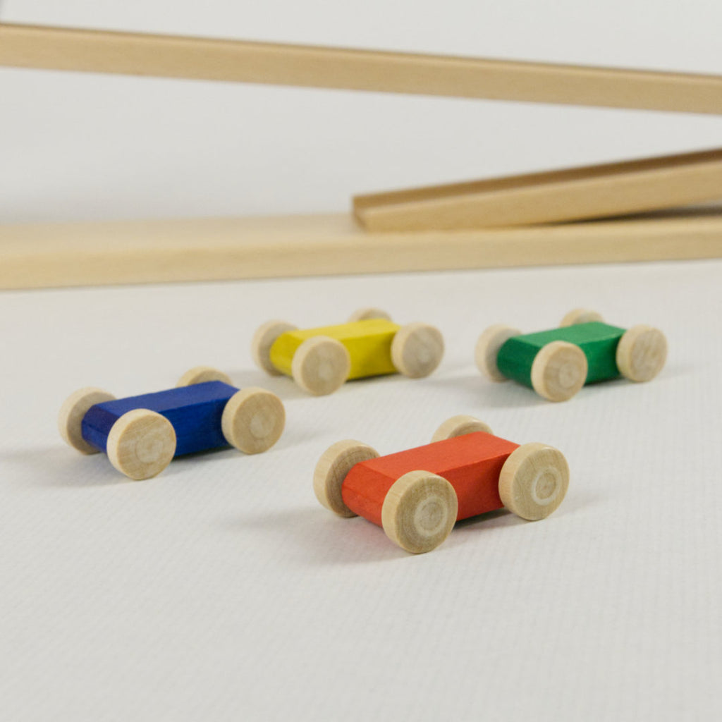 Detail vier bunte Flitzer aus Holz in den Farben rot, grün, blau und gelb