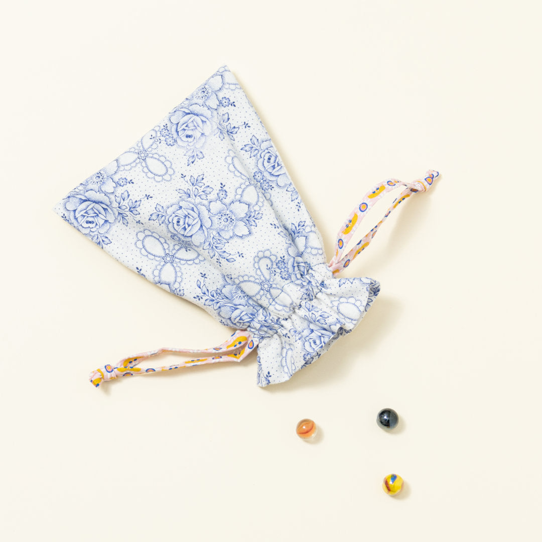 Hand-genähtes Murmelsäckchen mit Blumen-Muster in Weiß-Blau außen und gepunktet innen, geschlossen, inklusive einem individuellem Set aus einer großen Glas-Murmel und zwölf kleinen Glas-Murmeln