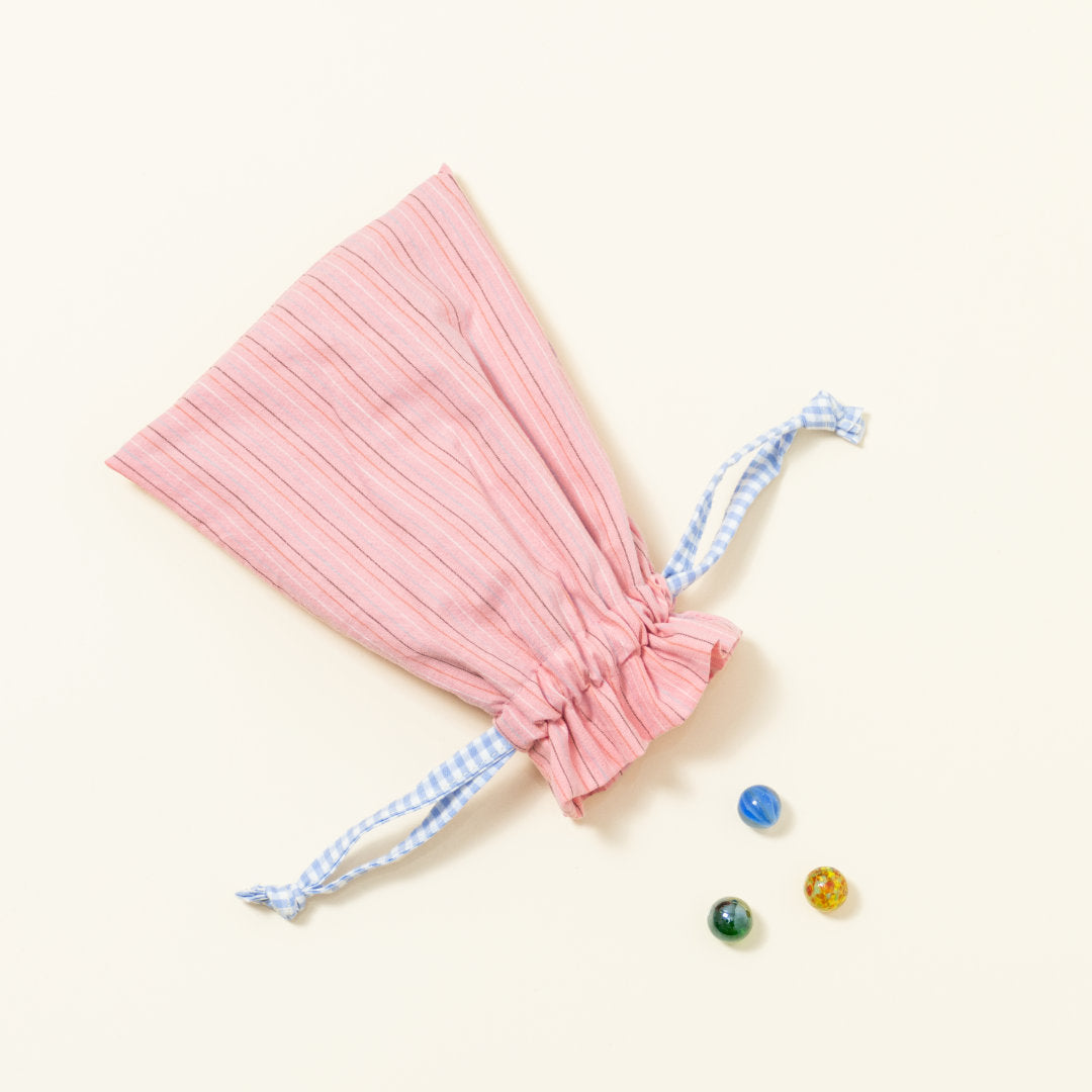 Hand-genähtes Murmelsäckchen mit Streifen-Muster in Rosa außen und gepunktet in Beige-Schwarz innen, geschlossen, inklusive einem individuellem Set aus einer großen Glas-Murmel und zwölf kleinen Glas-Murmeln
