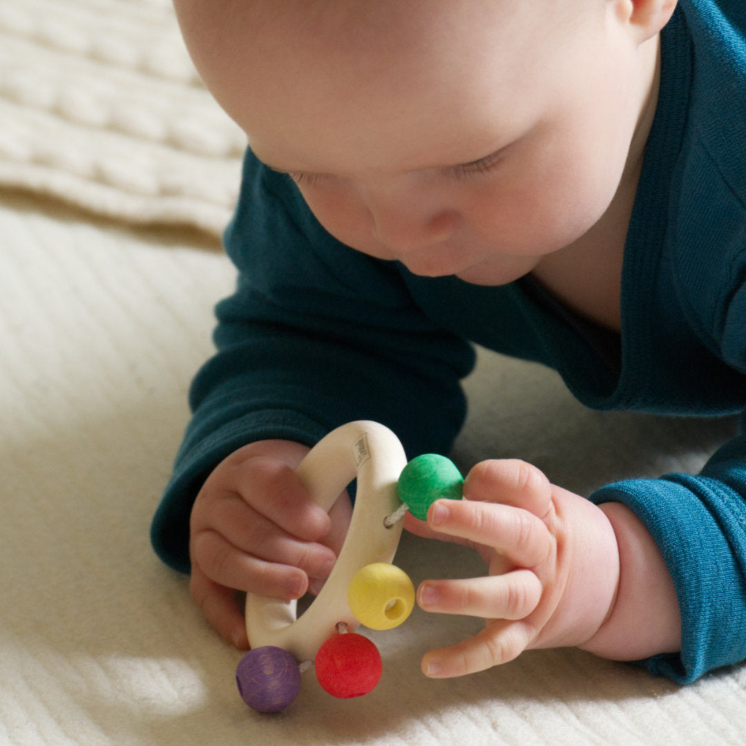 Baby spielt mit den bunten Perlen des Beissrings