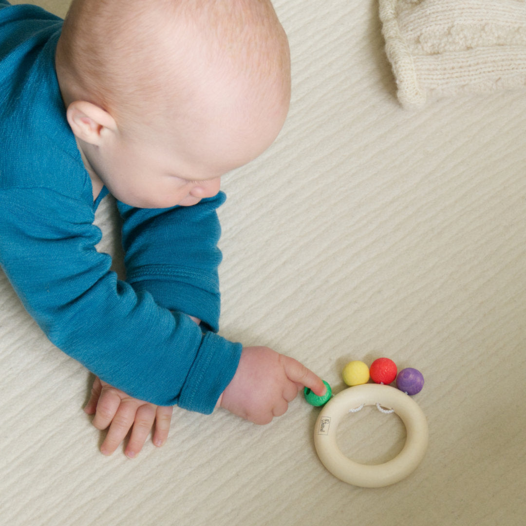 Baby spielt mit den bunten Perlen des Beissrings