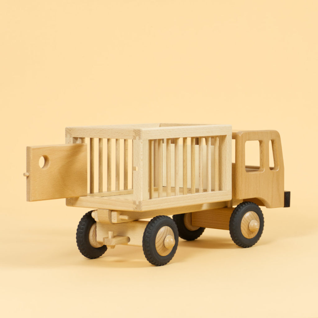 Holzfahrzeug Zirkuswagen für Tiere aus naturlackiertem Buchenholz und Reifen aus Vollgummi, Anhänger mit Gitterstäben an der Seite und geöffneter Tür hinten.