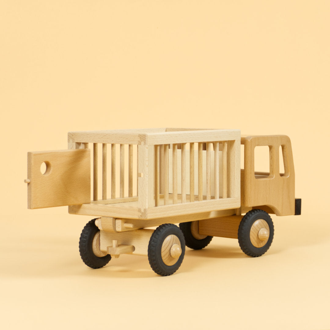 Holzfahrzeug Zirkuswagen für Tiere aus naturlackiertem Buchenholz und Reifen aus Vollgummi, Anhänger mit Gitterstäben an der Seite und geöffneter Tür hinten.