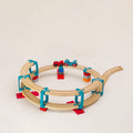 Das Adapter-Set Helix 1 von Yamba ermöglicht, mit Verbindungselementen für Klemmbausteine (DUPLO®, BioBUDDi®, Hubelino® usw.) und Schienen (BRIO®, IKEA®, Eichhorn®, Hape® usw.) ein mehrstöckiges Säulensystem aufzubauen. Das Set enthält 24 Elemente für zwei Schleifen nach oben. Enthalten sind LinkUp, Cross, Lift und Bar. Auf der zweistöckigen Bahn steht eine rote Holzeisenbahn mit schwarzen Rädern und türkisfarbenem Anhänger. Beide Zugteile sind magnetisch gekoppelt.