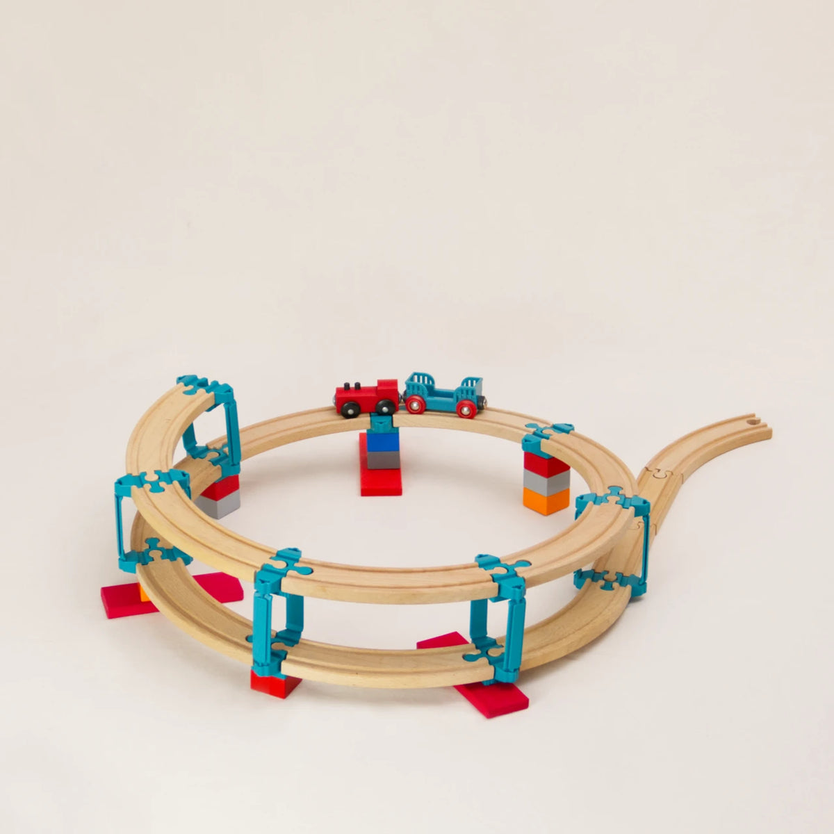 Das Adapter-Set Helix 1 von Yamba ermöglicht, mit Verbindungselementen für Klemmbausteine (DUPLO®, BioBUDDi®, Hubelino® usw.) und Schienen (BRIO®, IKEA®, Eichhorn®, Hape® usw.) ein mehrstöckiges Säulensystem aufzubauen. Das Set enthält 24 Elemente für zwei Schleifen nach oben. Enthalten sind LinkUp, Cross, Lift und Bar. Auf der zweistöckigen Bahn steht eine rote Holzeisenbahn mit schwarzen Rädern und türkisfarbenem Anhänger. Beide Zugteile sind magnetisch gekoppelt.