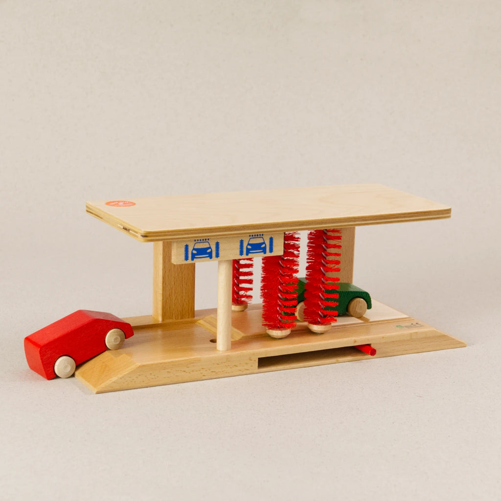 Waschanlage von Beck aus Holz. Die vier Bürsten sind in rot. Ein grünes und rotes Auto fahren durch.