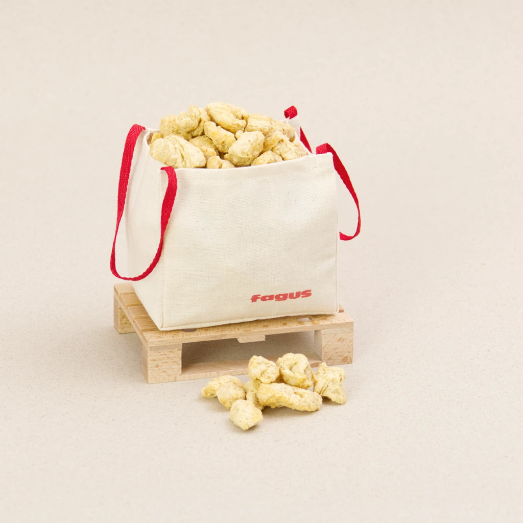 Ein Big Bag von fagus aus heller Baumwolle mit zwei roten Trageschlaufen. Der Big Bag ist mit Schüttmaterial gefüllt und steht auf einer fagus Europalette.