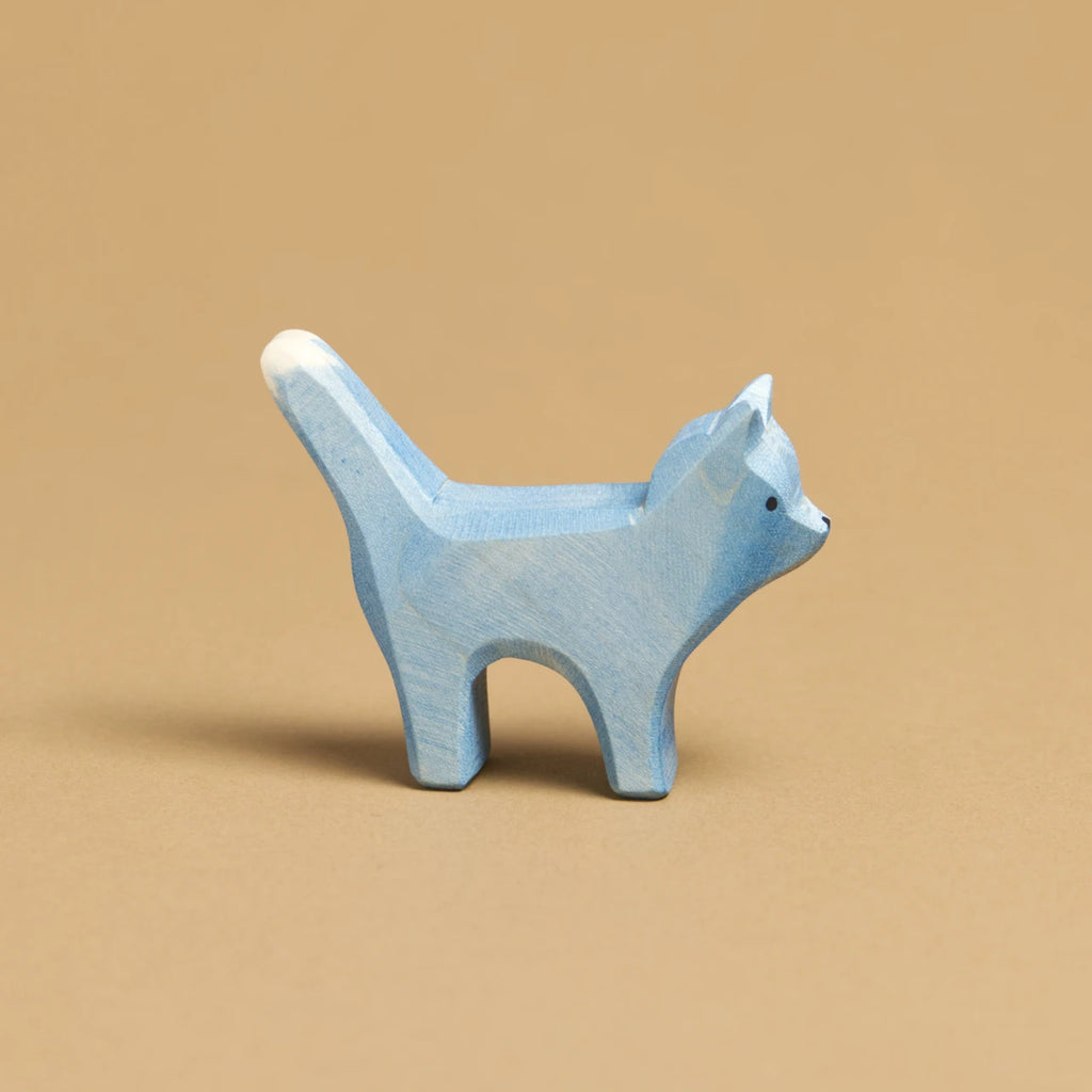 Eine blaue Katze, im Profil nach rechts schauend, ist von Ostheimer aus Naturholz gefertigt. Ihr Schwanz und ihre Ohren sind nach oben hin gerichtet.