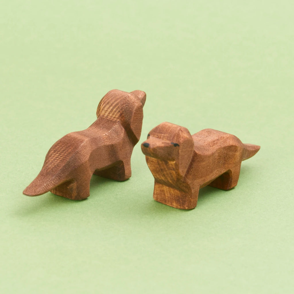 Zwei Dackel von Ostheimer aus Holz zum Spielen. In der Farbe braun. Beide stehen schräg zueinander.