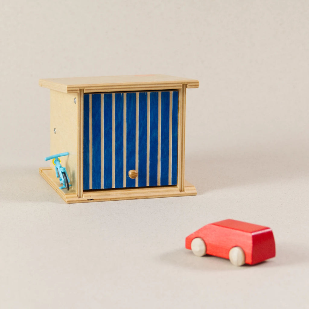 Doppelgarage von Beck zum Spielen, aus Holz. Das Garagentor ist blau und lässt sich aufklappen. Ein rotes Auto aus Holz ist dabei.