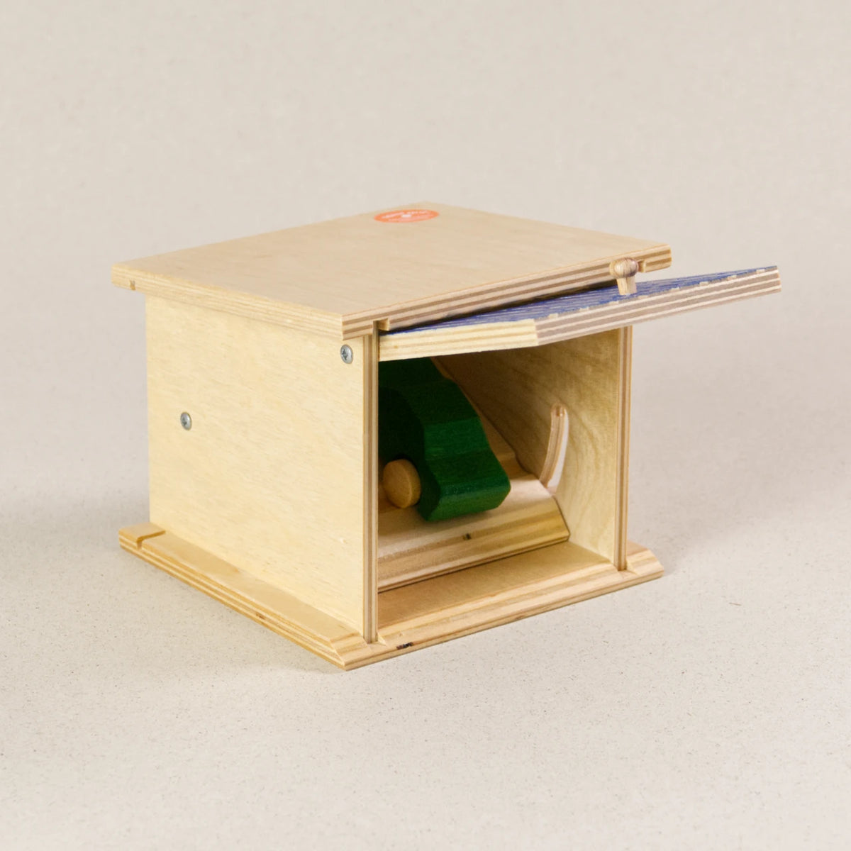 Doppelgarage von Beck zum Spielen, aus Holz. Das Garagentor ist blau und ist im aufgeklappten Zustand, darin befindet sich ein grünes Auto aus Holz.