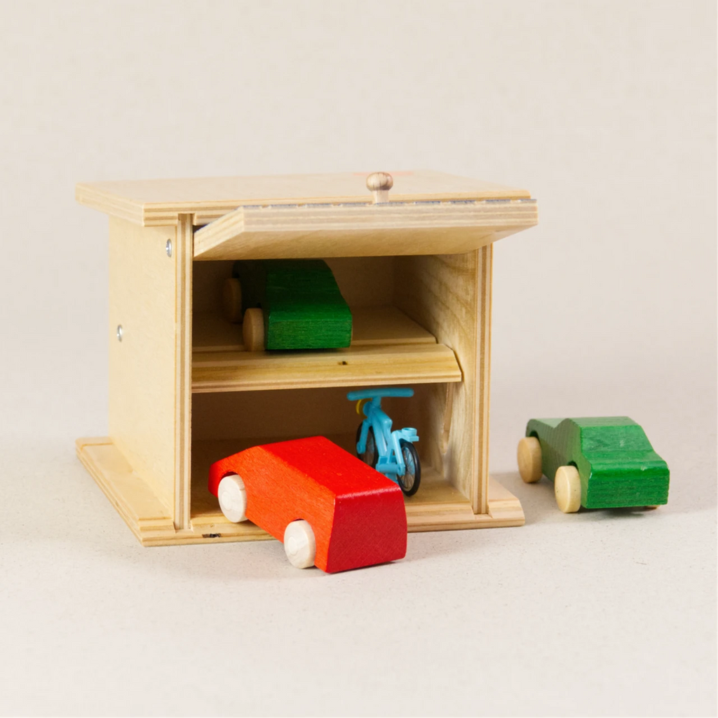 Doppelgarage von Beck zum Spielen, aus Holz. Das Garagentor ist blau und ist aufgeklappt. Ein grünes und rotes Auto sind in der Garage.