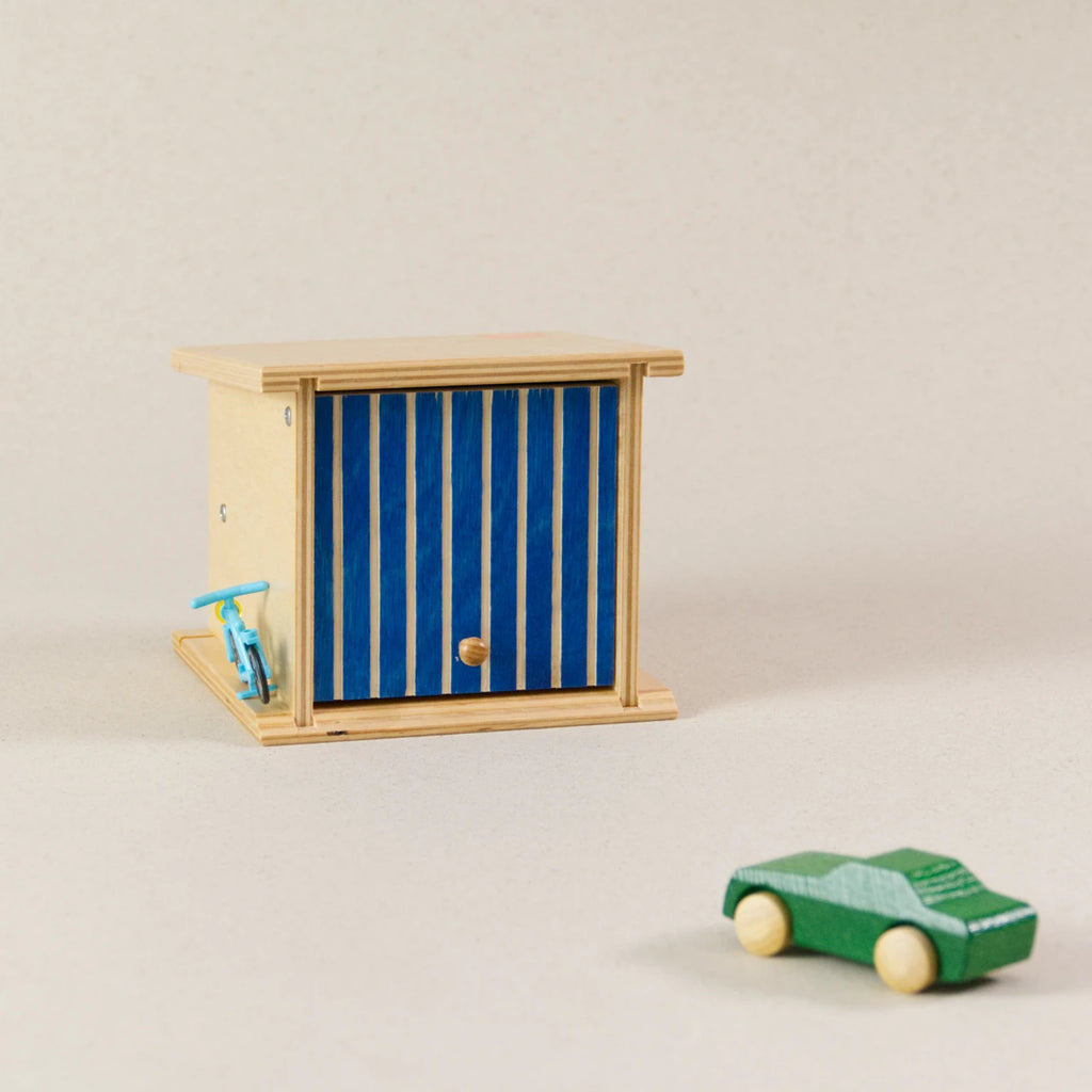 Doppelgarage von Beck zum Spielen, aus Holz. Das Garagentor ist blau und lässt sich aufklappen. Ein grünes Auto aus Holz ist zusätzlich zu sehen.