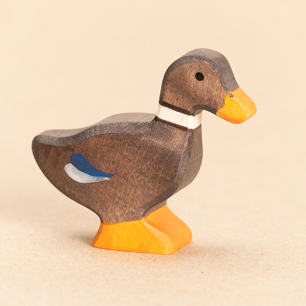 Ente aus Holz. Braun bemalt mit blauen Federakzenten und orangenem Schnabel und Entenpaddel. Nahaufnahme