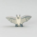 Handgefertigte Fledermaus Holztiger Figur aus naturbelassenem Holz. Die Fledermaus hat ausgebreitete graue Flügel mit feinen dunkleren Linien, einen cremefarbenen Körper und ein freundliches Gesicht mit kleinen schwarzen Augen und einem dezenten Lächeln. Perfekt als Holztier Spielzeug für Kinder oder als stilvolle Halloween Deko
