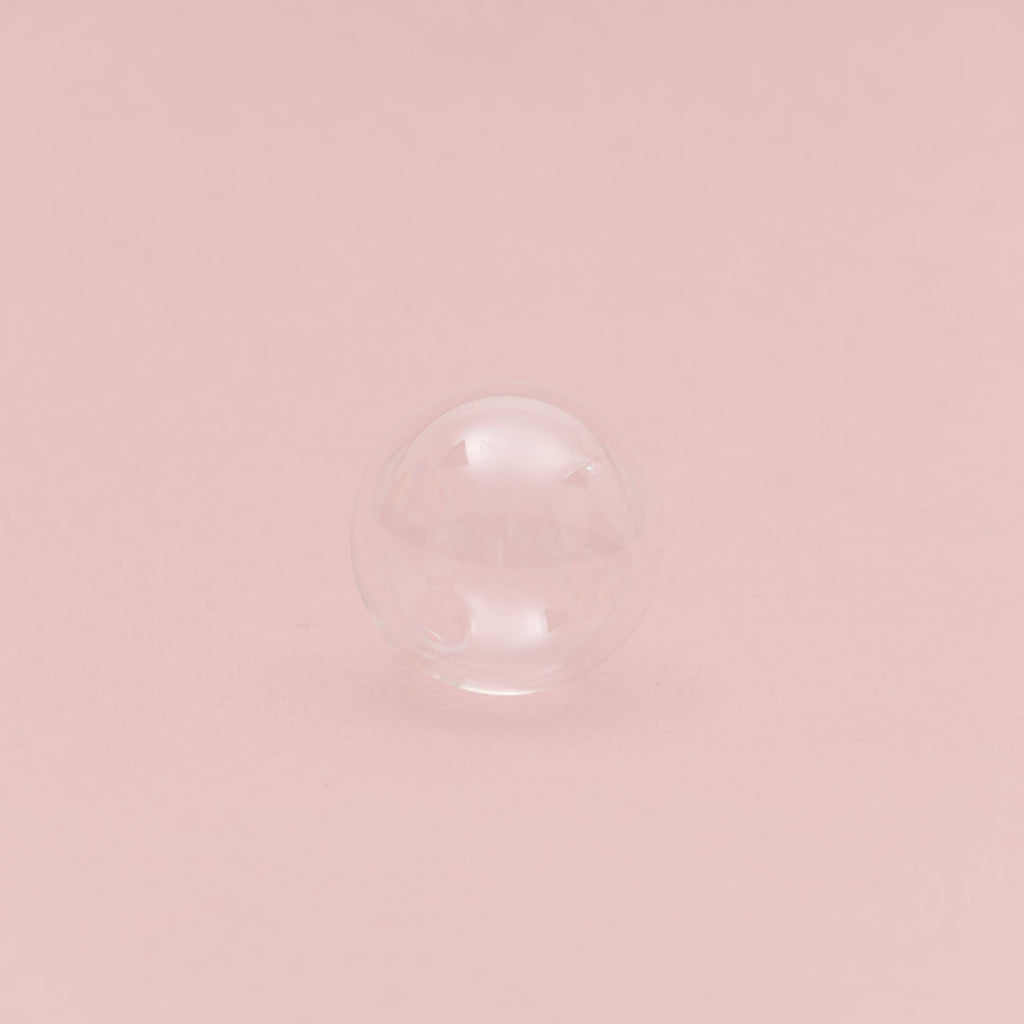 Gläserne Kugel auf rosa Hintergrund.