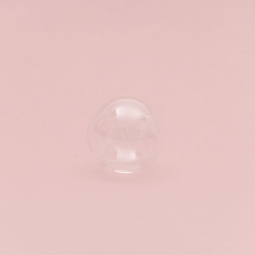 Gläserne Kugel auf rosa Hintergrund.