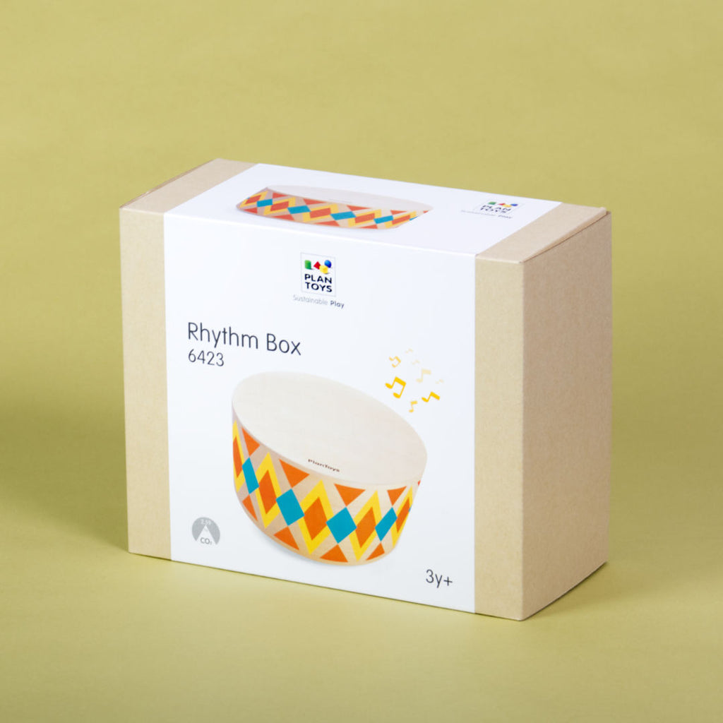 Verpackung der runden Handtrommel von Plan Toys. Das helle Holz ziert ein orange, blau, gelbes Rauten bzw. Dreiecksmuster.