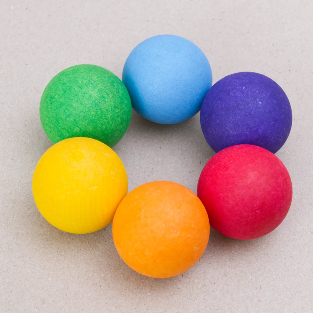 Fröhliche Kombination aus sechs bunten Holzkugeln von GRIMM'S (grimms) in Regenbogenfarben. Die Kugeln sind in einem Kreis angeordnet und leuchten in den Farben Rot, Orange, Gelb, Grün, Blau und Violett. Perfekt als kreatives Spielzeug oder dekoratives Element – ideal in Kombination mit dem großen Regenbogen von GRIMM'S für fantasievolle Bau- und Spielmöglichkeiten.