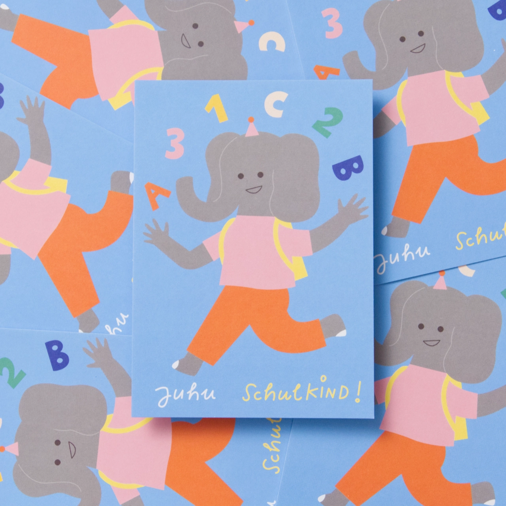 Mit fröhlichem Hopserschritt und leuchtenden Augen läuft ein kleines Elefantenkind in roter Hose, rosafarbem T-Shirt und mit gelbem Schulranzen seinem ersten Schultag entgegen. Über seinem Kopf tanzen die bunten Zeichen 1, 2, 3 und ABC. Auf blauem Hintergrund steht in Handschrift „Juhu Schulkind“. Das Bild zeigt Vorder- und Rückseite der Karte sowie mehrere Exemplare im Hintergrund. Die Rückseite ist fast weiß und trägt unten einen kleinen Schriftzug der Illustratorin.