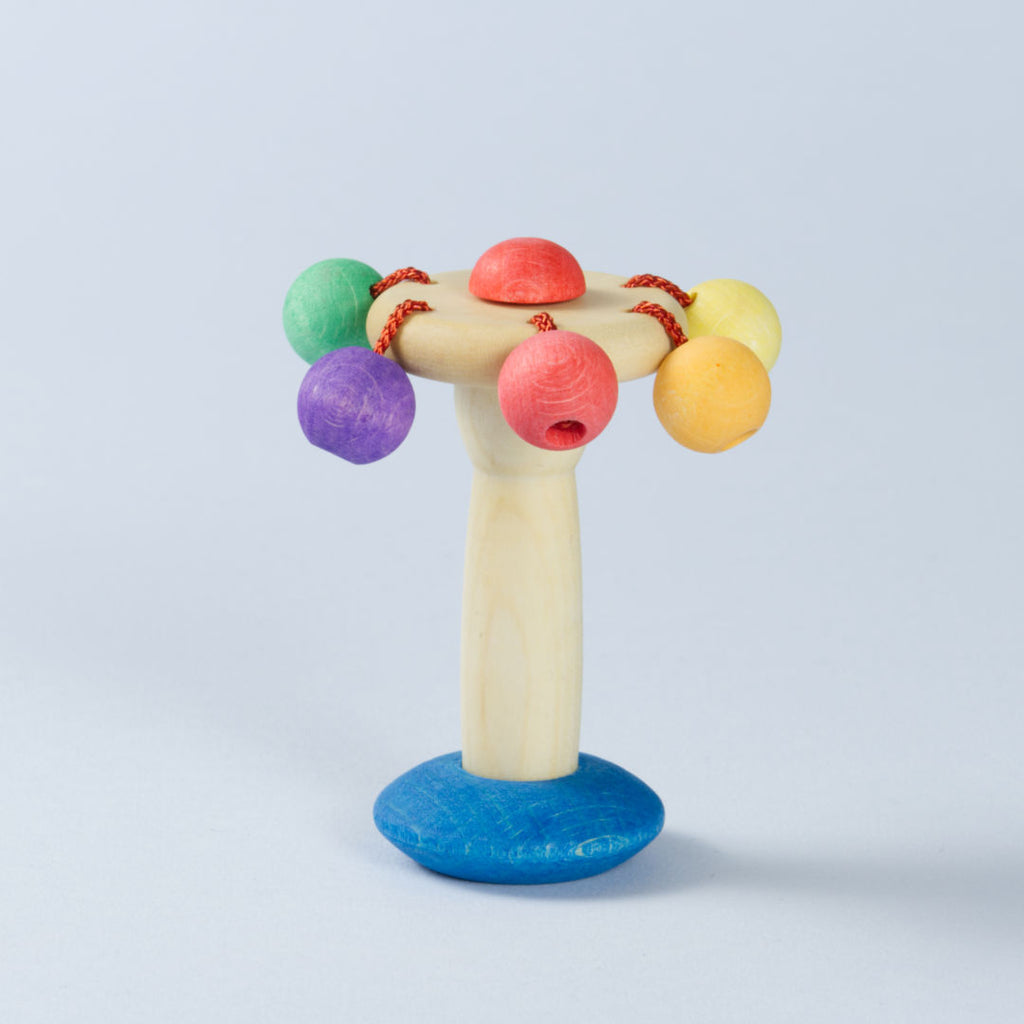 Stehende Karussellrassel aus Bio Holz, am Kopf belästigte, bunte Kugeln in Grün, Lila, Rot, Orange und Gelb.