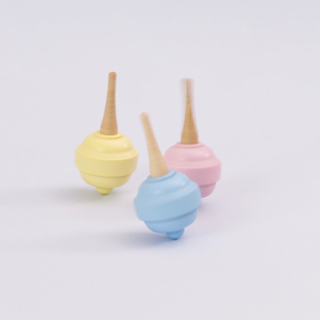 Pastellkreisel in gelb, blau und rosa aus Holz von Beck. Alle Kreisel drehen sich.