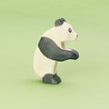 Ein tanzender Panda aus Holz ist stehend in der Seitenansicht zu sehen, er schaut nach rechts und hebt die Pfoten. Er hat weißes Fell und seine Ohren, Augen, Arme und Beine sind schwarz und geben ihm die klassische Pandamusterung. Er ist von der Marke Ostheimer.