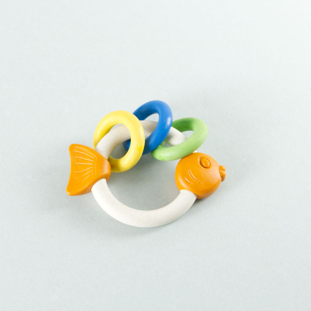 Antibakterielles Babyspielzeug Rasselring in Fischoptik. Drei kleine Ringe schmücken den großen Rassel Ring in Gelb, Blau und Grün.