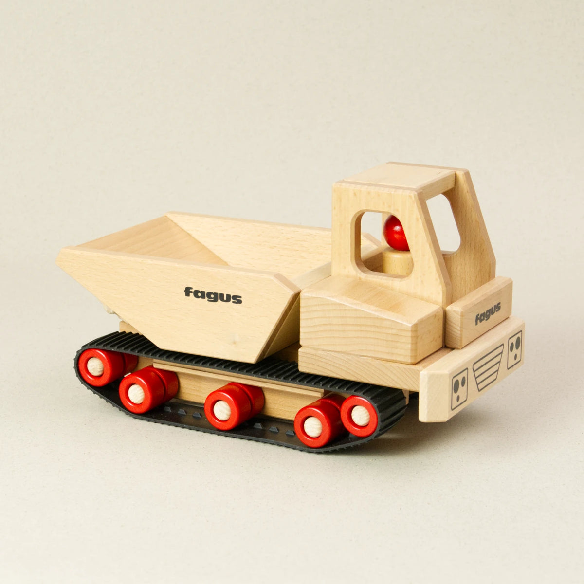Der fagus Raupen Dumper ist aus naturbelassenem Buchenholz, hat eine kantige Lademulde und fährt auf Gummiketten. In der Fahrerkabine sitzt eine Holzfigur.