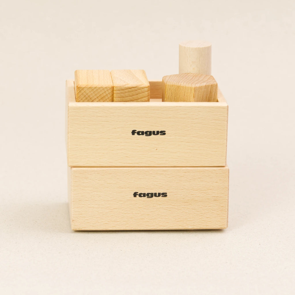 Zwei Stapelboxen von fagus aus naturlackiertem Buchenholz stehen aufeinander. Sie haben das fagus Logo auf der längeren Seite und die obere ist mit Holzstücken beladen.