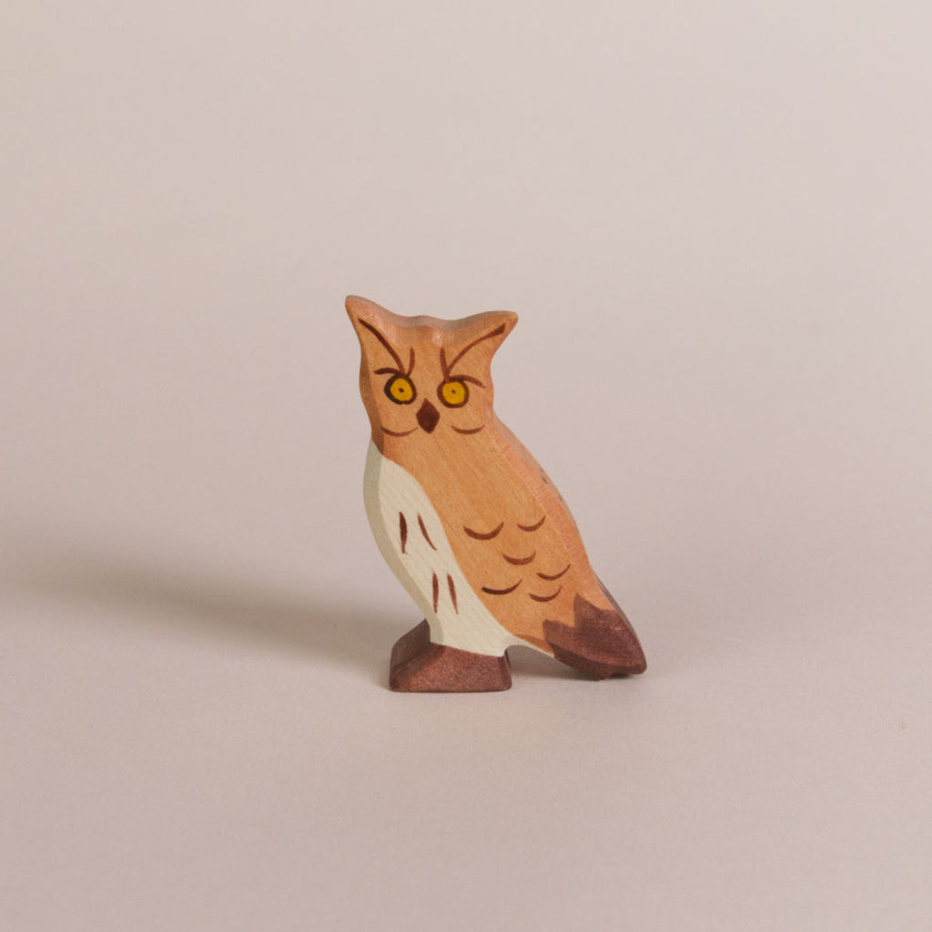 Ein Spielzeug Uhu aus Holz von der Marke Ostheimer. Er schaut mit seinen gelben runden Augen nach vorne und das Gefieder wird mit dunkelbraunen Pinselstrichen verdeutlicht.