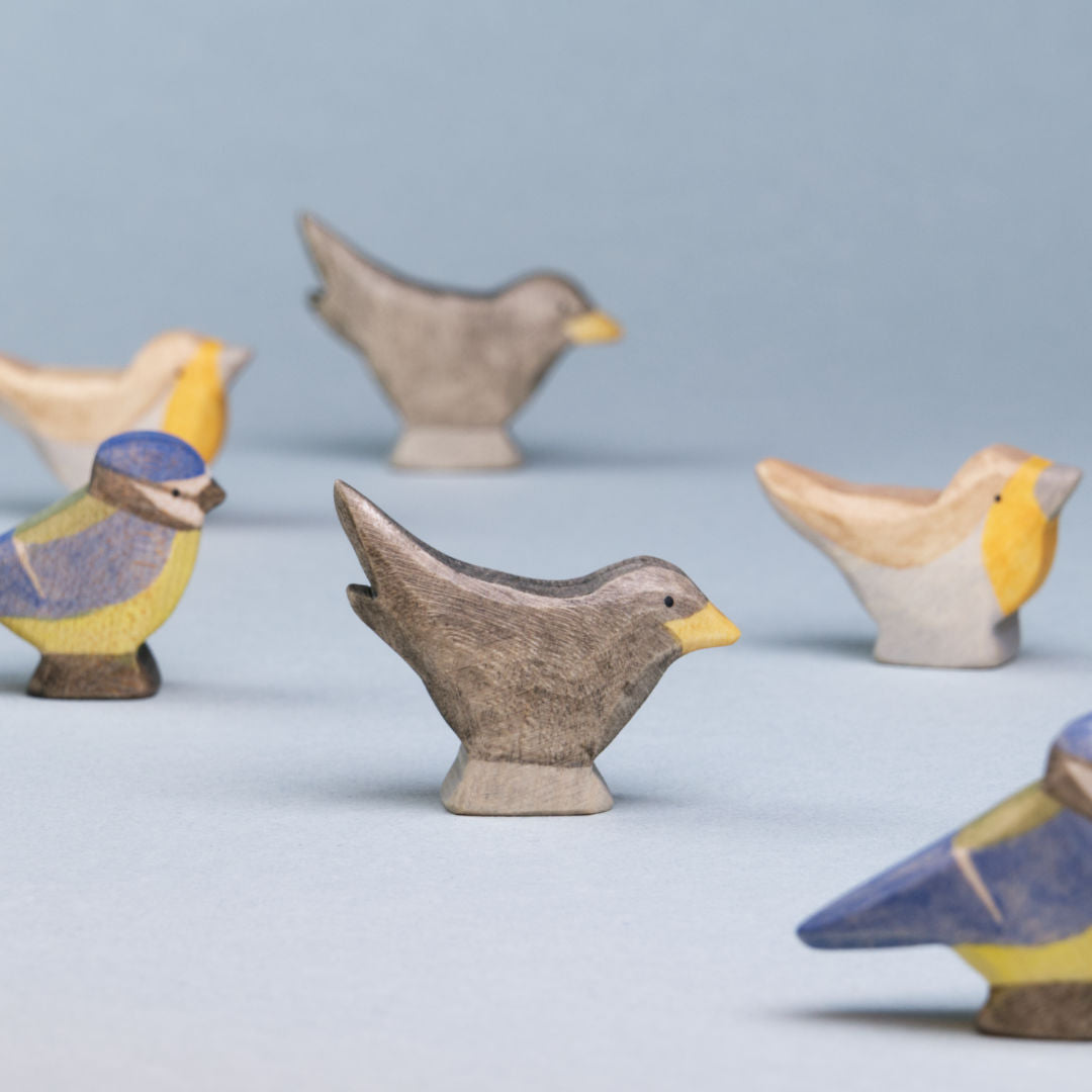 Komposition aus Holzvögeln der Firma Holzviecherl. Im Mittelpunkt Amsel, umspielt von Rotkelchen und Blaumeise.l