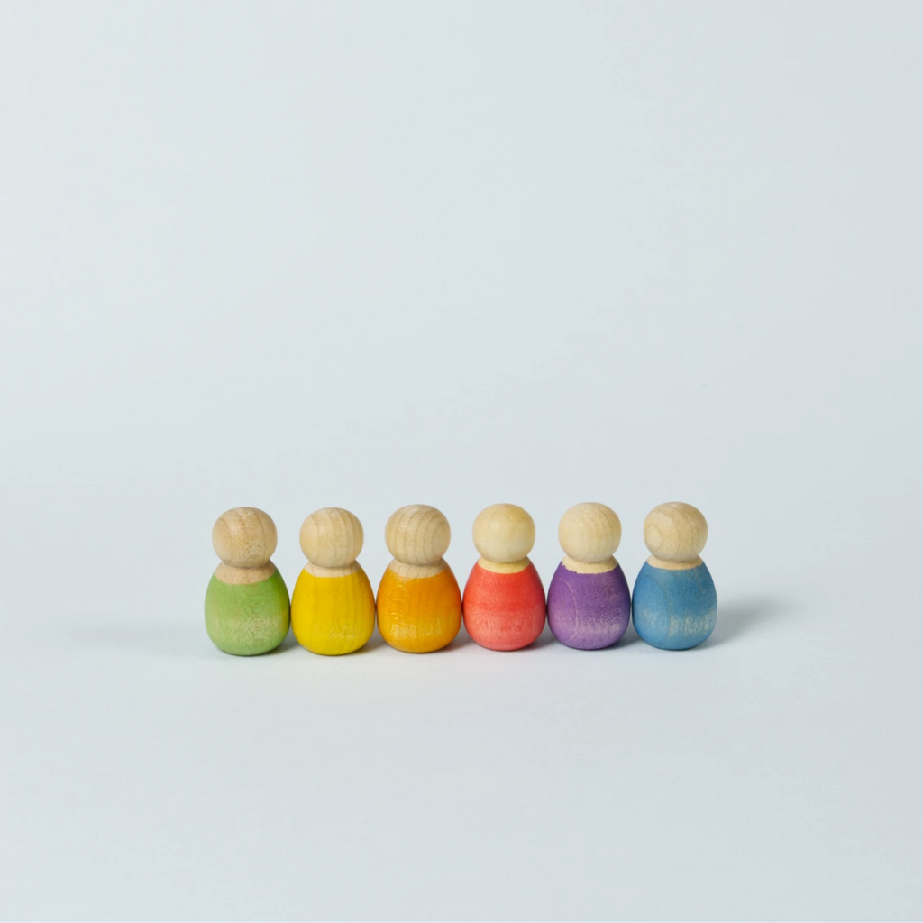 sechs kleine Babyholzfiguren in verschiedenen Farben in eine Reihe aufgestellt.