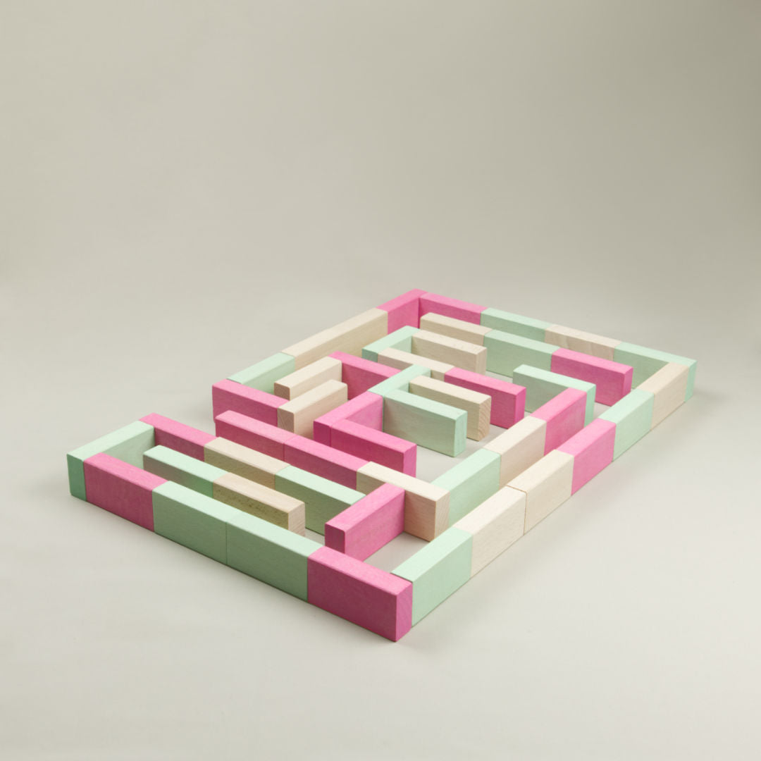Bunte Holz-Bausteine liegend aufgebaut in Naturholz, Rosa und Grün