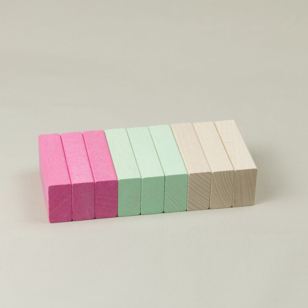 Bunte Holz-Bausteine liegend aufgereiht in Naturholz, Rosa und Grün
