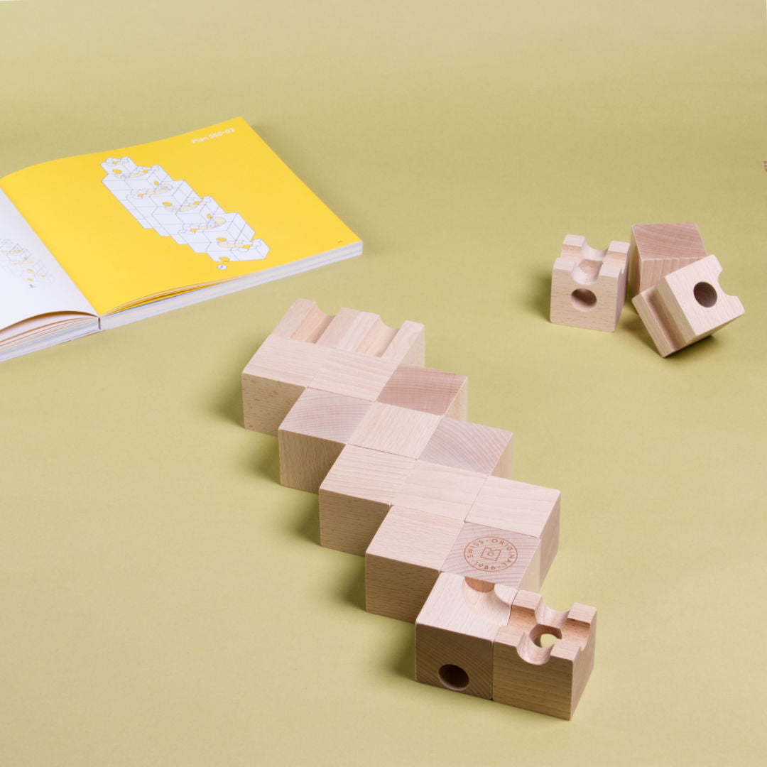 Erste Lage eines Murmelbahnaufbaus aus Holz des Standard 50 Sets von Cuboro aus dem dazugehörigen Buch.