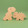 Das Dino Set 2 von Korxx, bestehend aus dem rechten Dino mit stacheligem Rücken und Kopf und linken Dino mit kleinem, aufrecht stehenden Körper. Beide schauen sich gegenseitig zur Bildmitte hin an und sind aus Kork gefertigt.