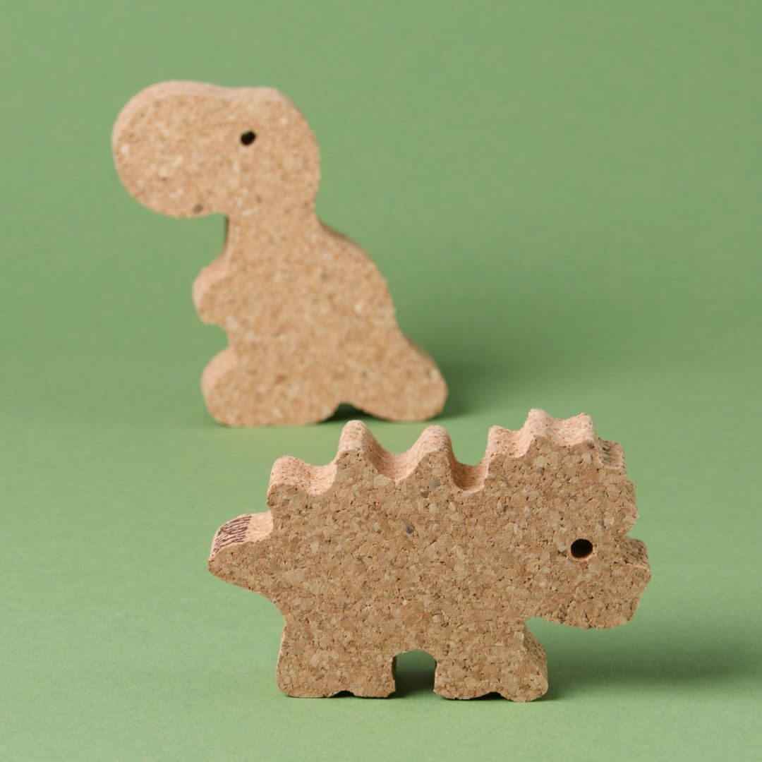Das Dino Set 2 von Korxx, bestehend aus einem Dino mit stacheligem Rücken Kopf, im Vordergrund und einem Dino mit aufrecht stehendem Körper im Bildhintergrund. Der Vordere schaut nach rechts und der sich im Hintergrund befindende schaut nach links. Beide sind aus Kork gefertigt.