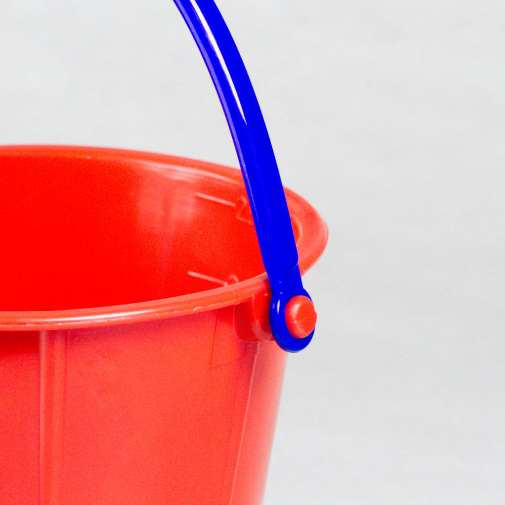 Detailansicht des großen roten Eimers aus hochwertigem Kunstoff von Spielstabil. Hat einen blauen, beweglichen Henkel.
