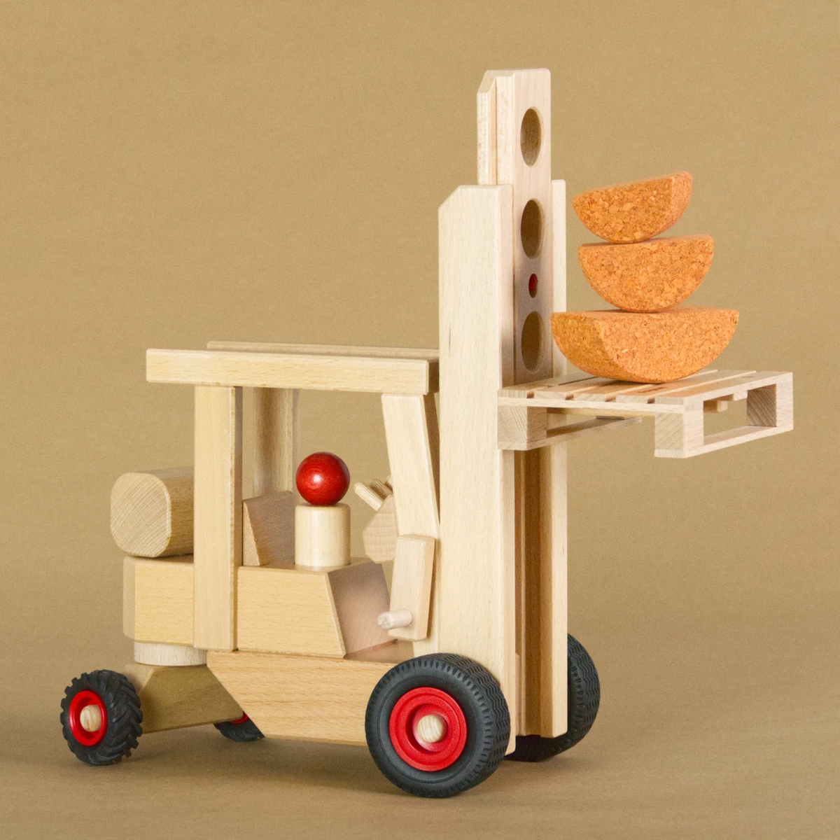 Gabelstapler aus naturlackiertem Buchenholz der Marke fagus mit Vollgummireifen. Auf der Ladegabel ist eine Holzpalette mit Ladegut, sie ist hochgehoben.