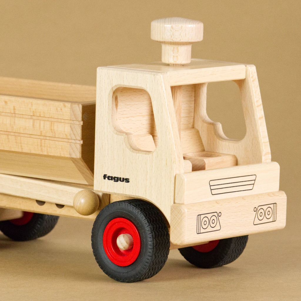 Muldenkipper-LKW von fagus aus naturlackiertem Buchenholz mit Vollgummireifen. Ansicht von vorne, auf dem Dach der leeren Fahrerkabine ist ein Lenkknopf.