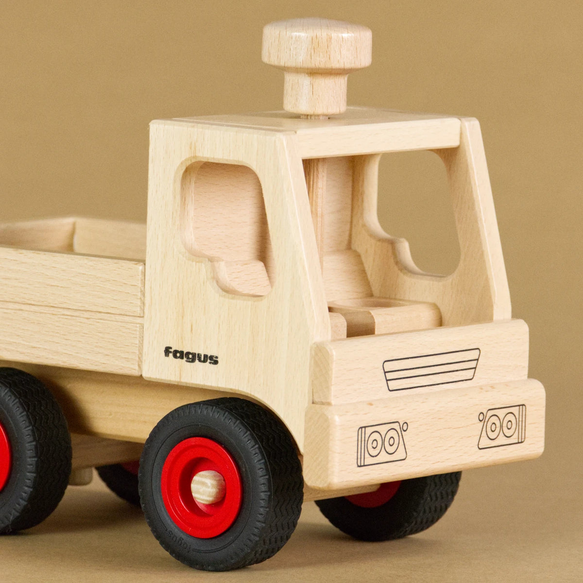 Unimog von fagus aus naturlackiertem Buchenholz, mit Vollgummireifen. Auf dem Dach der leeren Fahrerkabine ist ein Lenkknopf.